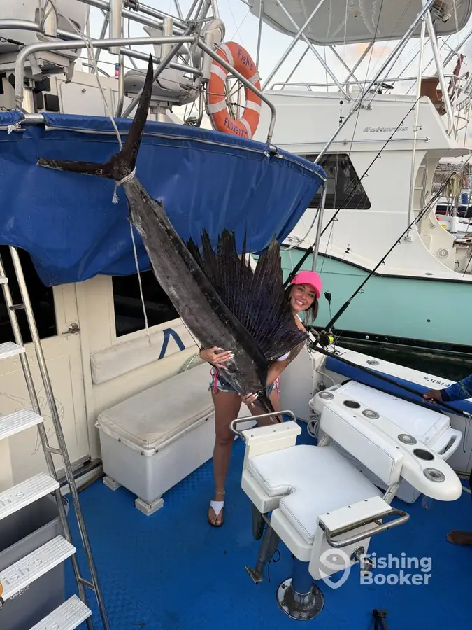Guest holding up a 9 ft sailfish aboard Fish’s