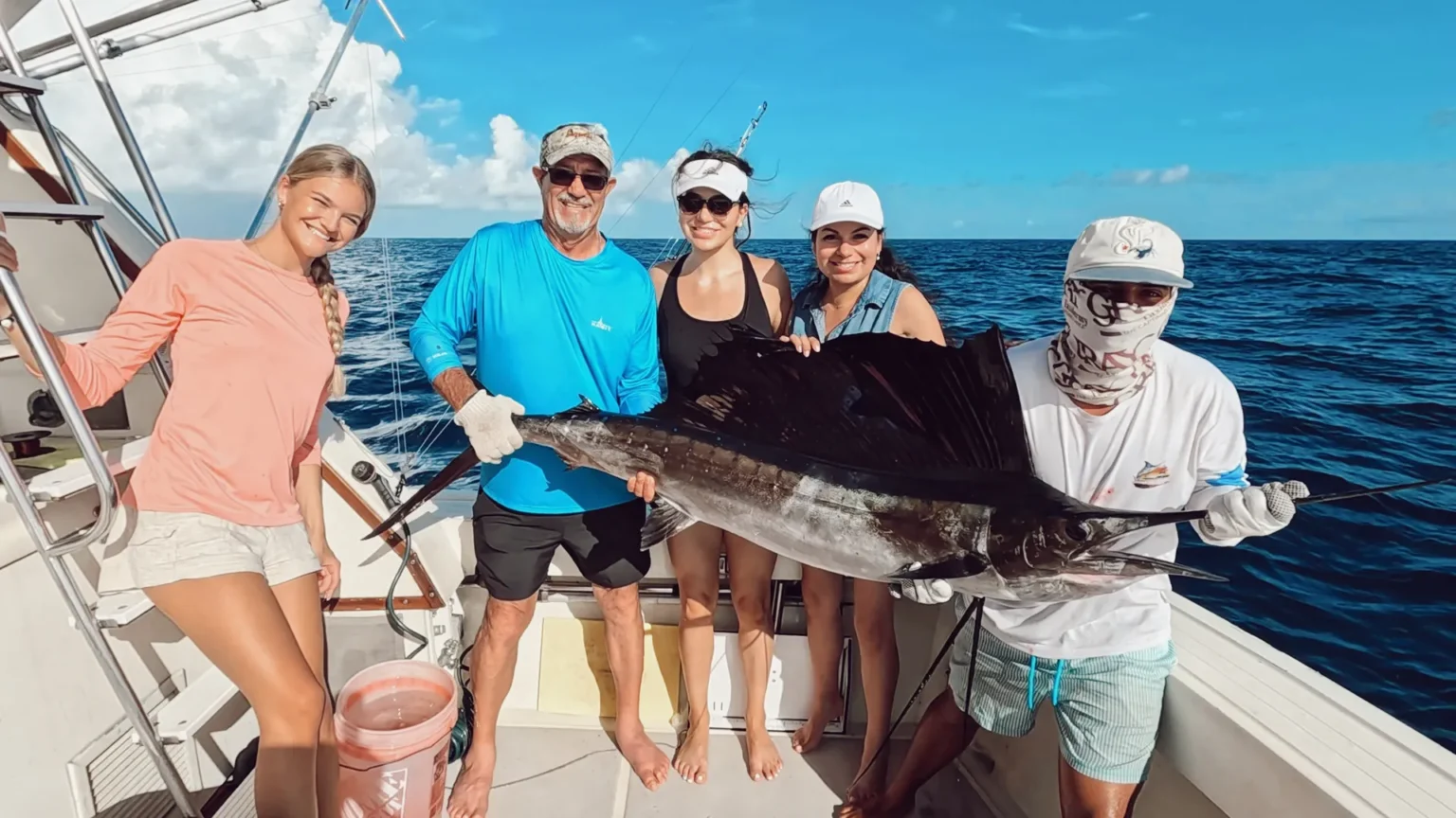Guests holding a sailfish caught on a private fishing charter in Cancún