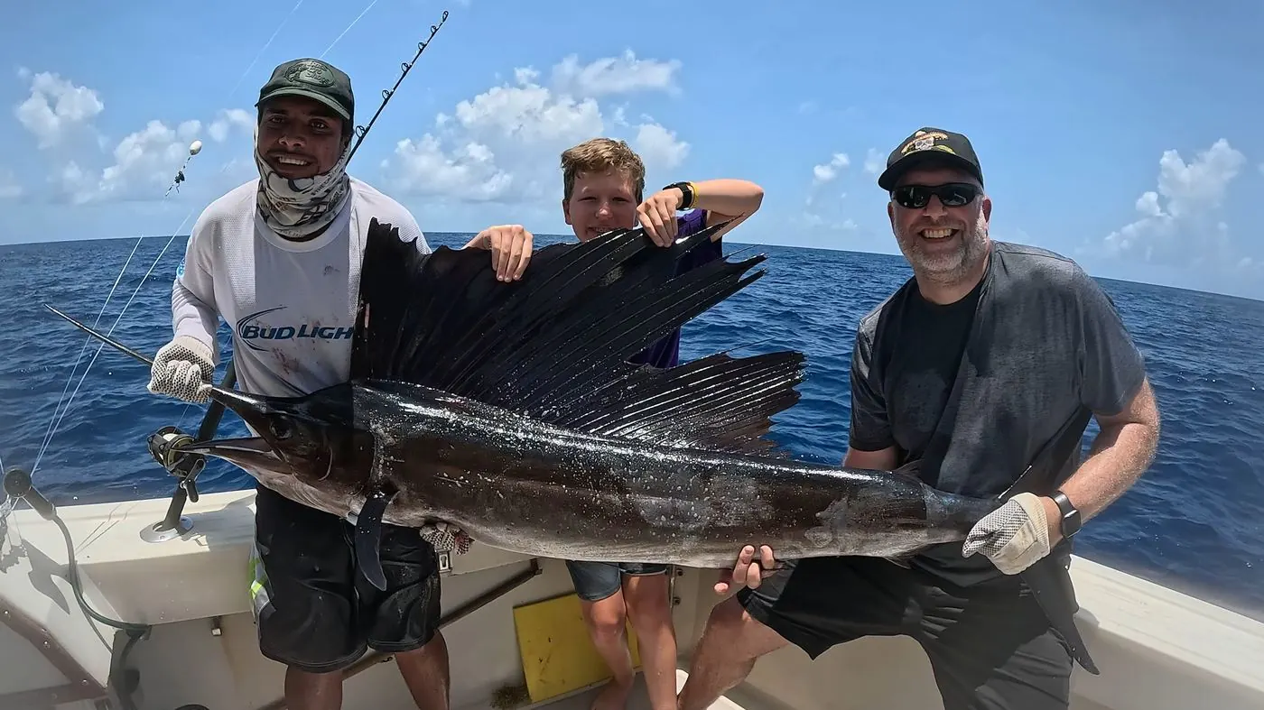 Guests holding a sailfish aboard before releasing it