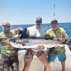 Anglers holding a large catch during a Cancun fishing trip.