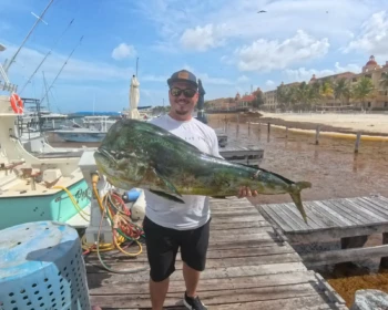 Guest holding a mahi-mahi caught on Fish’s in Cancún